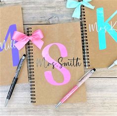 two notebooks with pink and blue ribbons on them, one has the number three