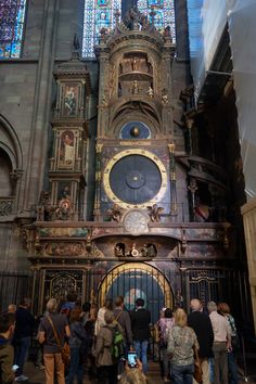 a group of people standing in front of a tall clock tower with stained glass windows