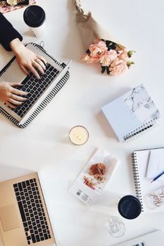 a white table topped with laptops next to flowers and other items on top of it