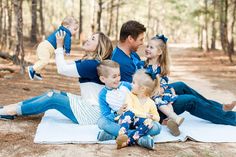 a family sitting on a blanket in the woods with their toddler son and sister