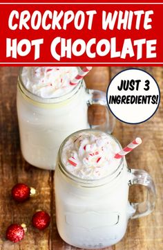 two mason jars filled with white hot chocolate and topped with candy canes on a wooden table