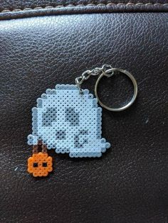 a cross stitch keychain with an orange and white pumpkin in the shape of a pixel