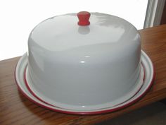 a white cake with red piping sitting on top of a wooden table next to a window