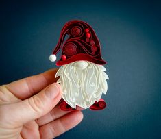 a hand holding an ornament shaped like a gnome