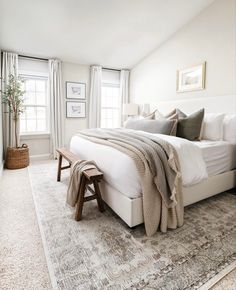 a bedroom with a large bed and rugs on the floor in front of two windows