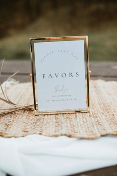 a sign sitting on top of a wooden table next to a white cloth covered tablecloth