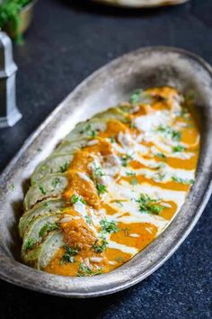 some food that is in a metal dish on a black table and it looks like something out of an old movie