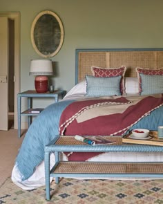 a bed with blue and red sheets in a bedroom next to a lamp on a table