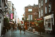 people are walking down the cobblestone street