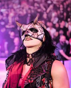 a woman wearing a cat mask in front of a crowd