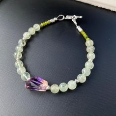 A bright and colorful Ametrine and Prehnite gemstone beaded bracelet to brighten up your day! This gorgeous boho stacking bracelet has the prettiest shaded Ametrine nugget focal stone. Ametrine is a stone that has both Citrine and Amethyst in it. The purple and yellow color is exquisite. The light lime green Prehnite round gemstone beads are 8mm. The closure is a sterling silver toggle clasp. Choose your bracelet size from the drop down menu before check out. It comes in size 6-8 inches. I use o Green Bohemian Crystal Gemstone Bracelet, Multicolor Amethyst Bohemian Bracelets, Bohemian Multicolor Amethyst Beaded Bracelets, Hand-strung Bohemian Amethyst Crystal Bracelet, Presents For Wife, Crystal Healing Bracelets, Natural Stone Bracelets, Gemstone Beaded Bracelets, Colorful Jewelry