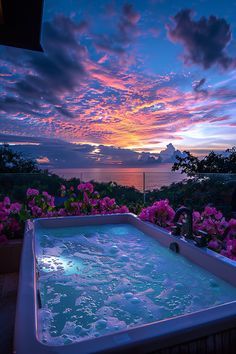 a hot tub sitting on top of a wooden deck next to pink flowers and trees