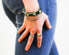 Indulge in bohemian charm with our Artisan Turquoise Leather Bracelet. This delightful piece boasts a rustic, variegated color. Each cuff is carefully sealed to preserve its beauty. The leather band measures 5/8" wide and features genuine turquoise cabochons, including a 12mm round center stone and two 10mmx12mm oval stones. Fastened securely with two button posts, this cuff is made to order and ethically sourced, ensuring that the genuine turquoise stones are mindfully selected. It's a unique a Green Bohemian Bracelets With Patina, Artisan Turquoise Hand Wrapped Wrap Bracelet, Artisan Hand Wrapped Turquoise Wrap Bracelet, Turquoise Hand Wrapped Wrap Bracelet, Earthy Turquoise Bracelet Jewelry, Green Bohemian Stackable Wrap Bracelet, Adjustable Turquoise Bracelet With Patina, Adjustable Turquoise Bracelets With Patina, Adjustable Multicolor Patina Jewelry