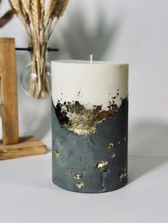 a white and black candle sitting on top of a table next to some dried flowers