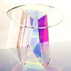 a clear glass table topped with a colorful vase