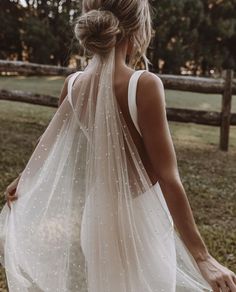 the back of a woman wearing a white wedding dress with sheer, beaded detailing