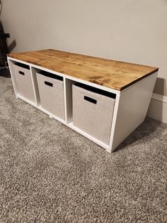 an entertainment center with three bins and a wooden top on carpeted flooring