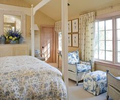 a bed sitting in a bedroom next to two chairs and a table with flowers on it