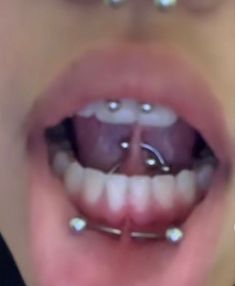 a close up of a person's mouth with piercings on it and teeth