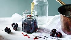 raspberry jam in a jar with fresh berries on the table next to it