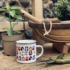 a coffee mug with pictures of dogs on it next to gardening tools and potted plants