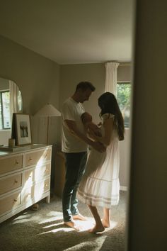 a man and woman standing in a room with a baby