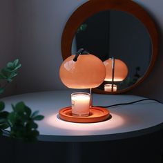 a table with a lit candle on it and a round mirror in the corner behind it