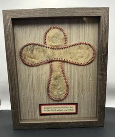 a wooden frame with an embroidered cross on it and a plaque in the middle that reads,