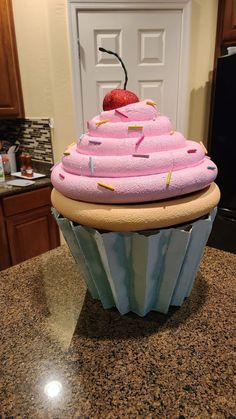 a cupcake with pink frosting and sprinkles on top sitting on a counter