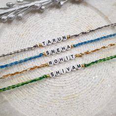 three bracelets with words written on them sitting on a white plate next to silverware