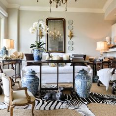 a living room with blue and white vases on the floor next to a couch