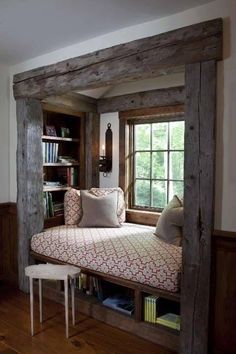 a window seat in the corner of a room with bookshelves and pillows on it