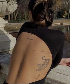 the back of a woman's body with tattoos on her upper and lower half