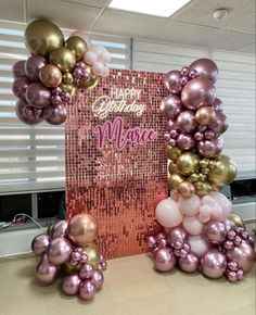 a pink and gold balloon arch for a birthday