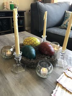 a table with candles, eggs and other decorations on it in a living room next to a couch