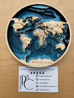 the wooden world map is on display in front of a business card