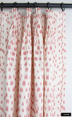 pink and white polka dot curtains hanging on a black rod