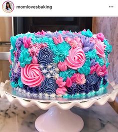 there is a large cake decorated with pink, blue and purple flowers on the top