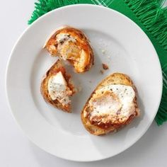 two pieces of bread on a white plate with green fringed placemat and fork