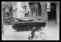 a man riding a bike next to a tank