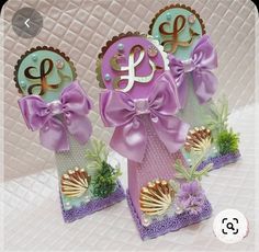 three small cards with purple bows and monogrammed letters on them, one has a seashell