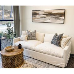 a living room filled with furniture and a painting hanging on the wall over a window