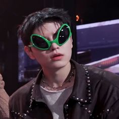 a young man wearing green goggles in front of a neon sign with lights on it