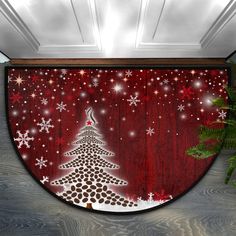 a door mat with a christmas tree and snowflakes on the bottom, in front of a red background