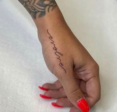 a woman's hand with a small tattoo on her left wrist and the word love is in cursive writing