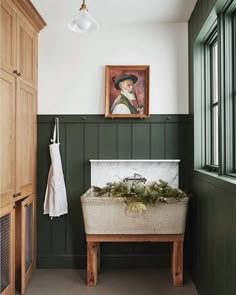 a bathroom with green paneling and a painting on the wall next to a bench