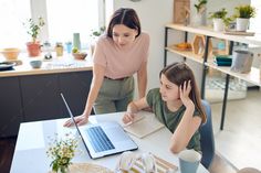 two women are working on laptops in the kitchen - stock photo -'s