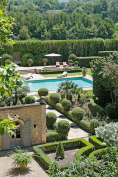 an outdoor pool surrounded by hedges and trees