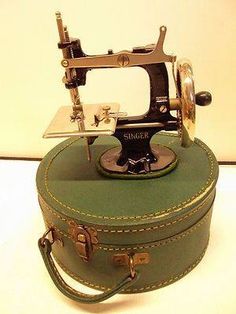 an old sewing machine sitting on top of a green suitcase