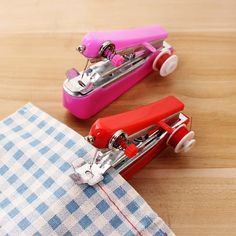 two small sewing machines sitting on top of a wooden table next to a pink pair of scissors